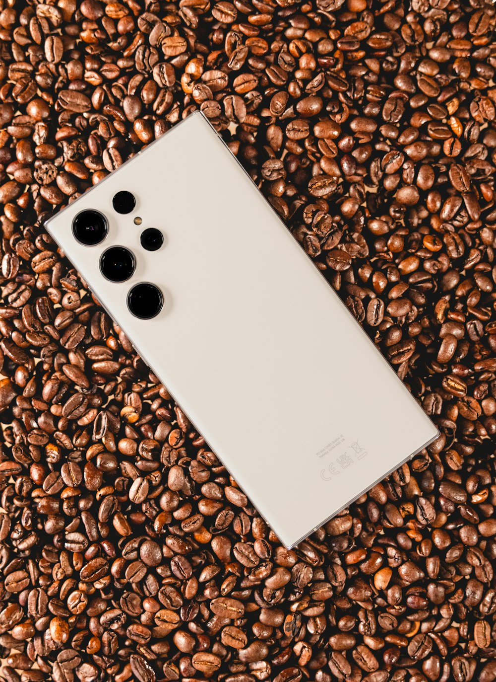 a white cell phone sitting on top of a pile of coffee beans