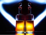Elegant glass bottles filled with golden herbal oils glowing softly against a dark green background.