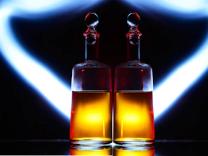 Elegant glass bottles filled with golden amber oils placed on a dark bronze surface.