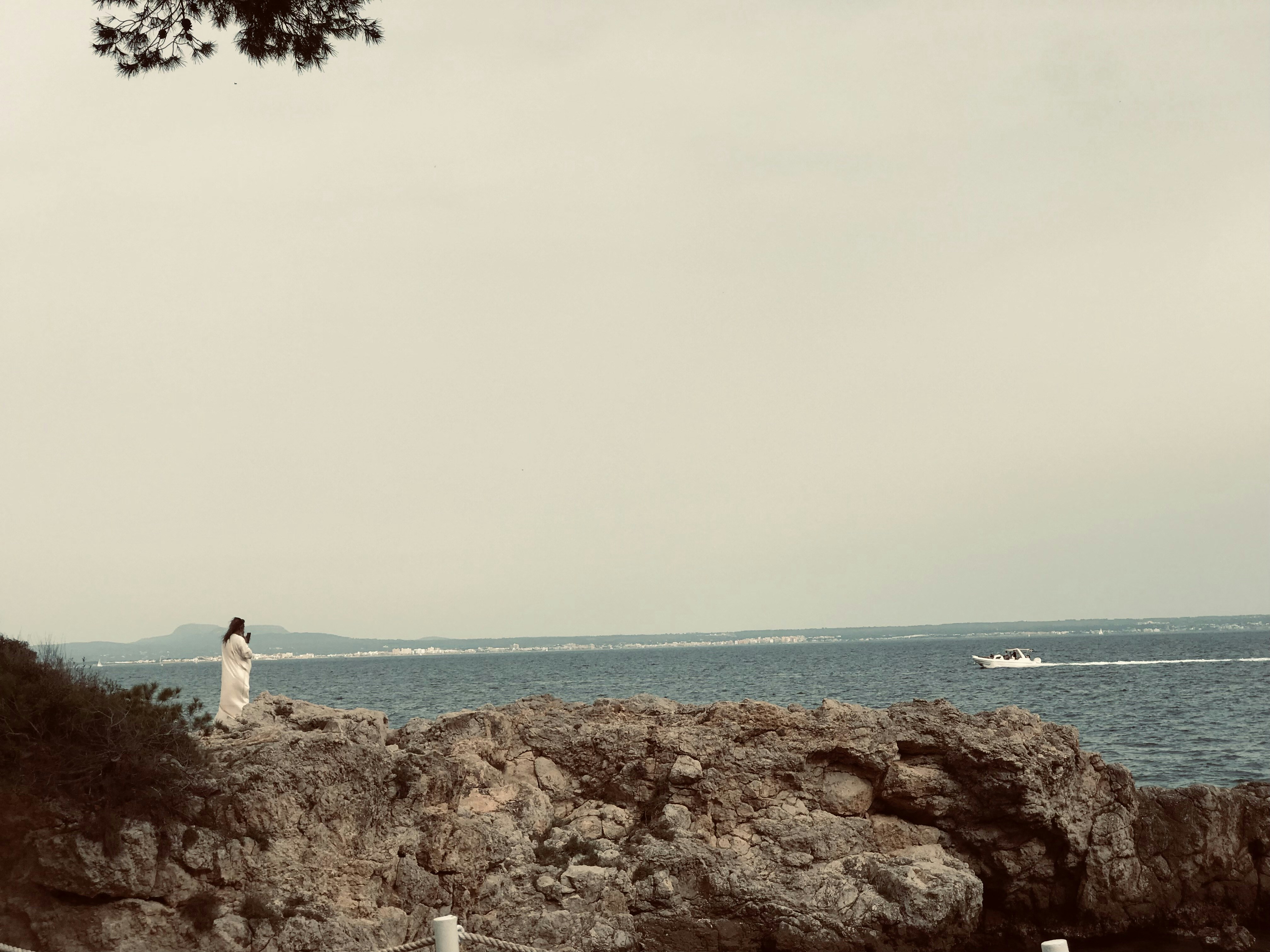 A person standing on a rock near the ocean photo – Free Spain Image on ...