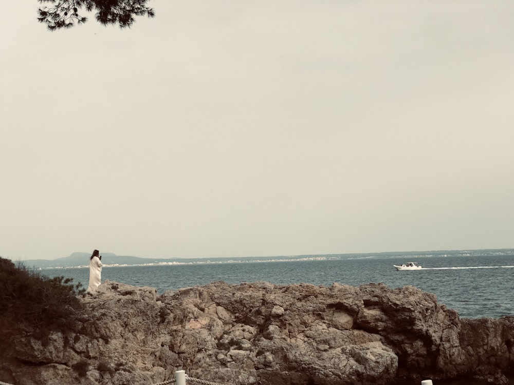 a person standing on a rock near the ocean