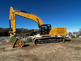 Yellow excavator working on a construction site with clear blue sky