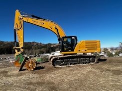 A yellow excavator digging at a construction site under a clear sky