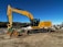 A hydraulic excavator digging soil on a large construction site under a clear blue sky.