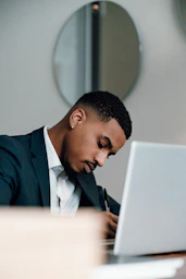 a man in a suit writing on a laptop