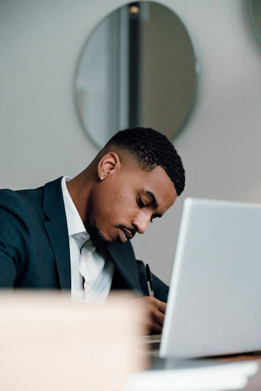 a man in a suit writing on a laptop