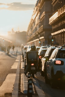a person riding a motorcycle down a street next to parked cars