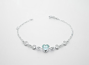A delicate silver bracelet featuring a central heart-shaped blue gemstone flanked by two smaller round white stones on each side, all linked with a fine chain.