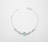 Delicate silver bracelet with a heart-shaped blue gemstone and four round clear gemstones evenly spaced along the chain. It has a simple chain link design and a clasp for securing it.