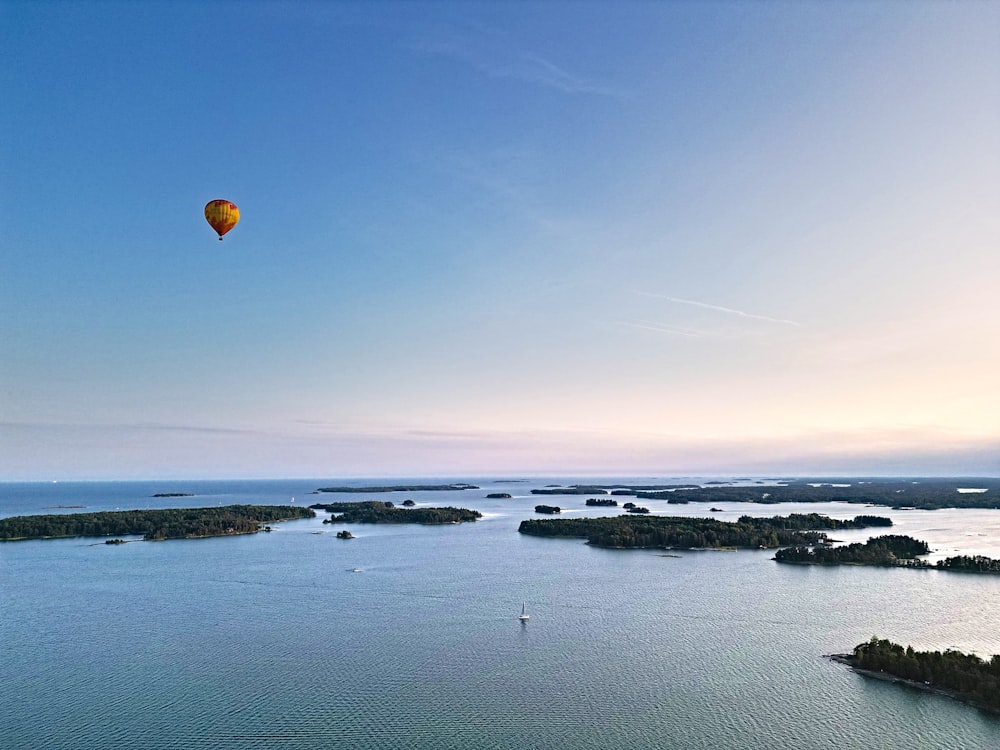 a hot air balloon flying over a large body of water