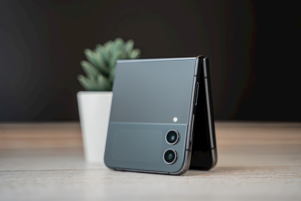 a cell phone sitting on top of a table next to a potted plant