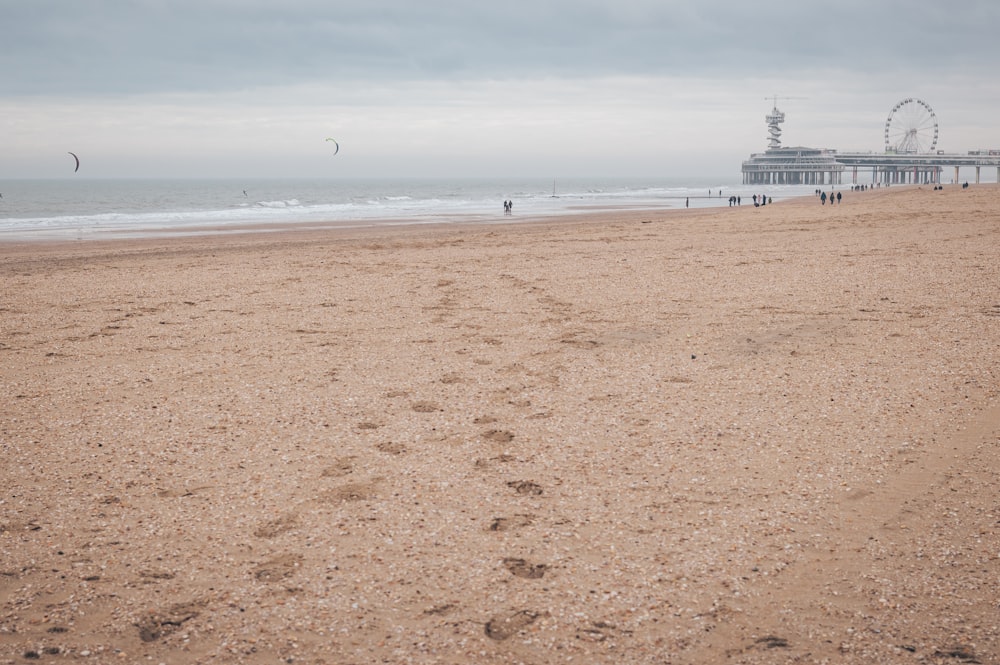 a sandy beach with a pier in the background