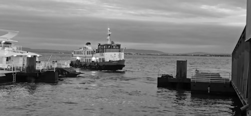 An autonomous boat docking smoothly at a busy inland port under cloudy skies.