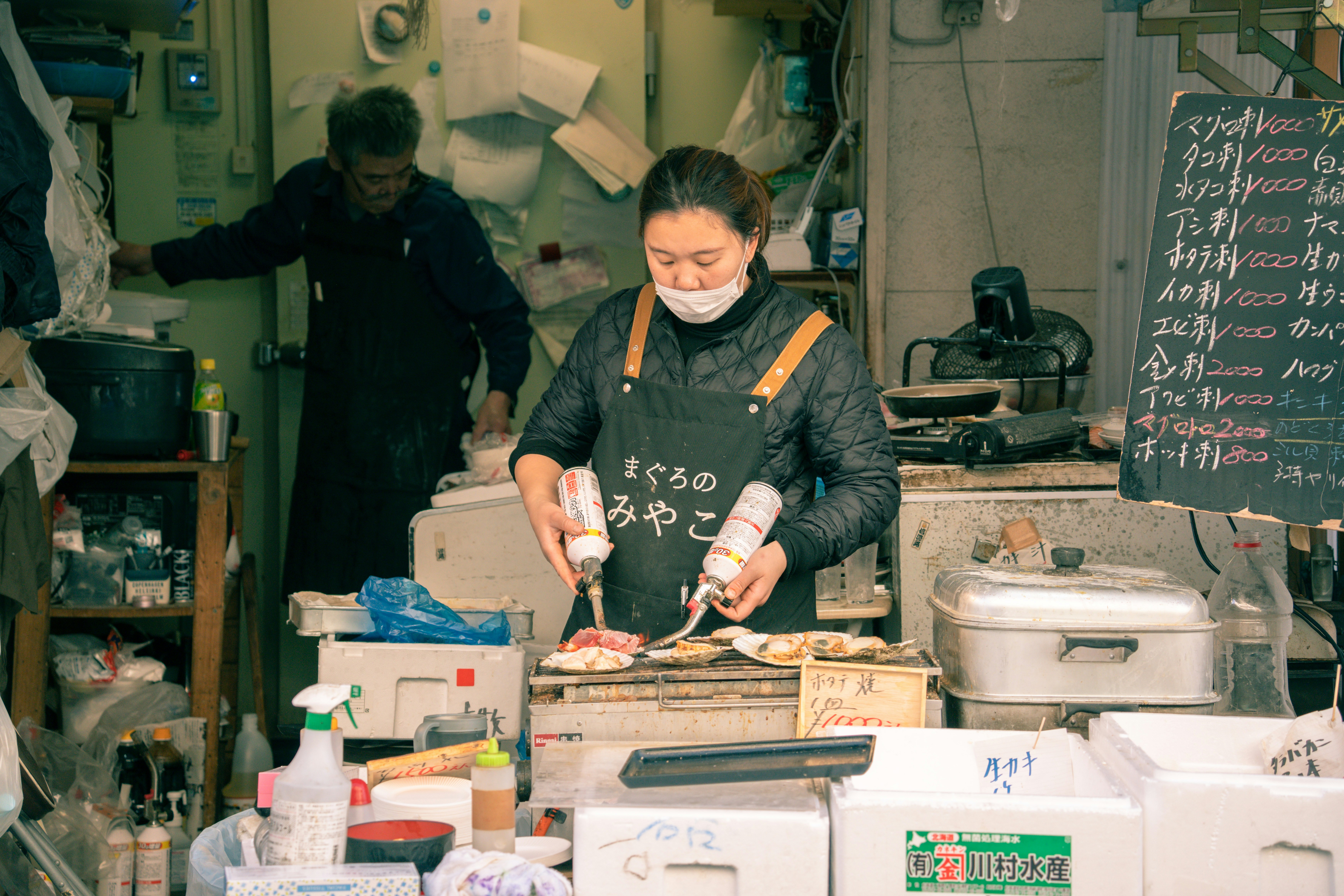 a woman wearing a face mask preparing food in a kitchen, 