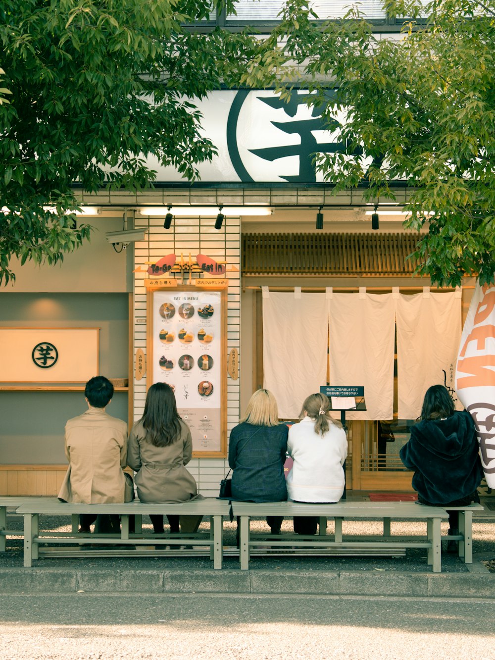 a group of people sitting on a bench in front of a store