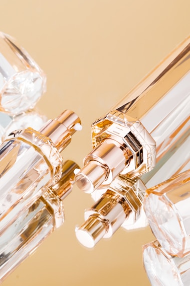 Close-up of elegant perfume bottles with golden accents on a reflective surface.