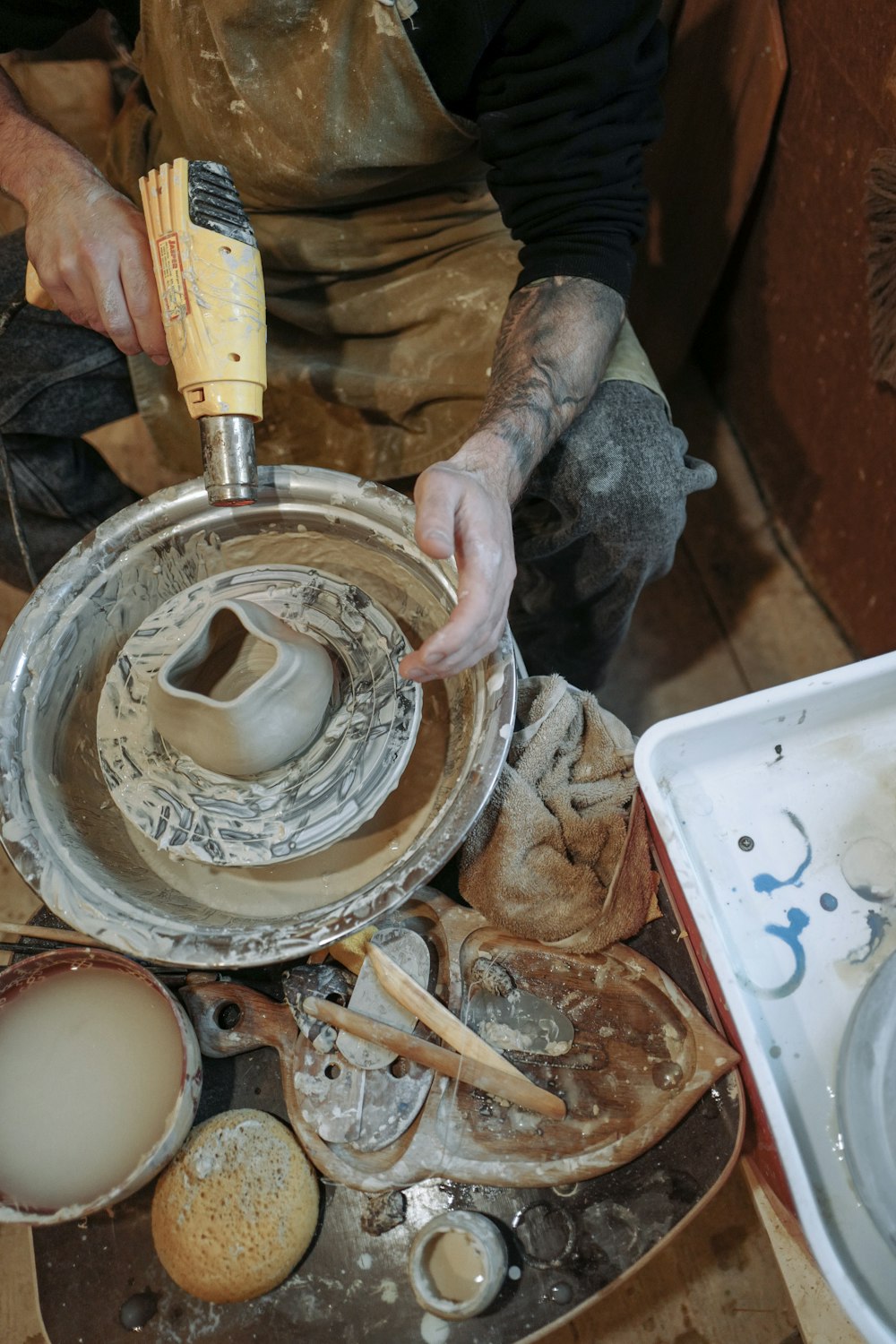 Un hombre está trabajando en una rueda de cerámica