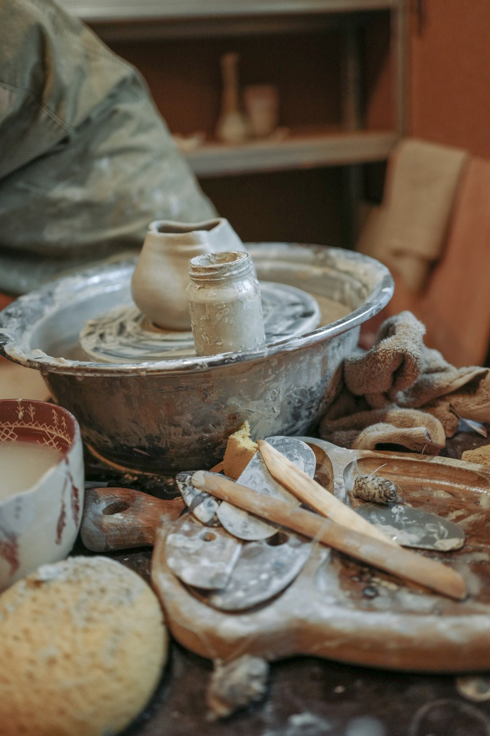 Un torno de alfarero rodeado de cerámica y otros artículos