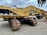 Several large yellow excavators with 'CAT' branding are parked on a gravel surface under a cloudy sky. The machines feature large metallic tracks and articulated arms, typically used for heavy-duty digging and construction work.