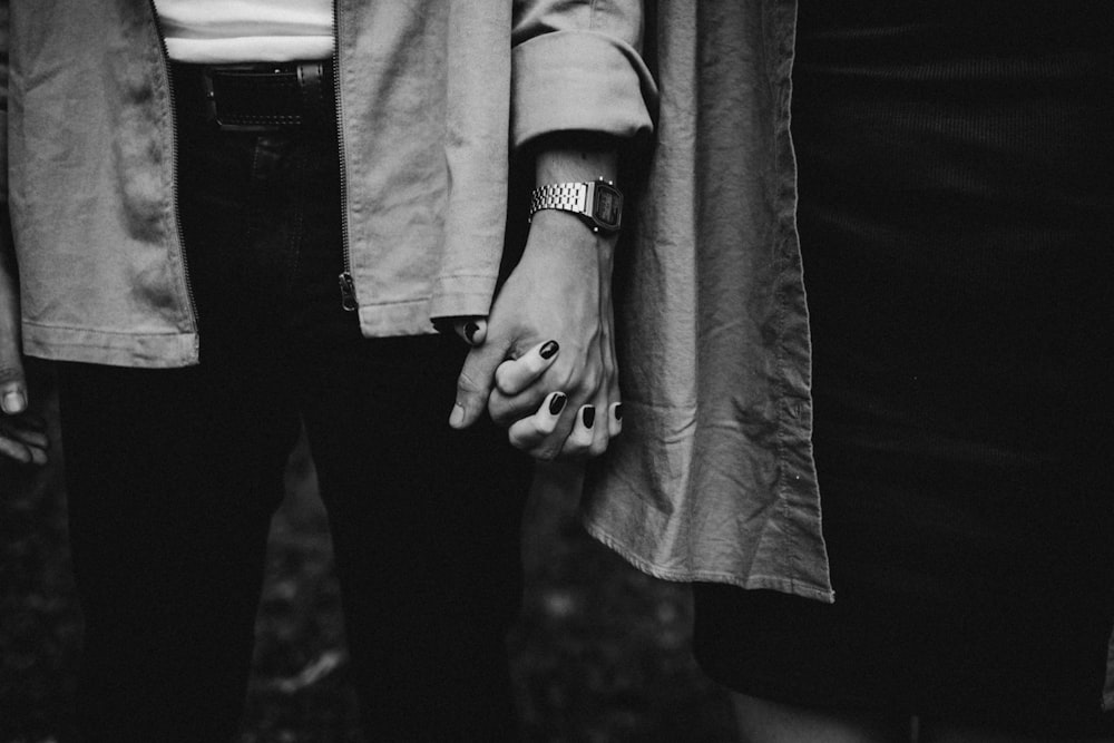 a black and white photo of two people holding hands