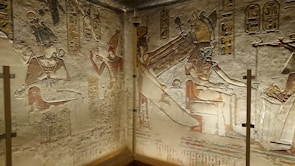 Ancient Egyptian wall carvings depict figures in regal attire, featuring pharaohs and deities. Hieroglyphics are inscribed above and around the figures, adding to the historical richness. The artwork demonstrates intricate detailing and craftsmanship typical of ancient Egyptian art.