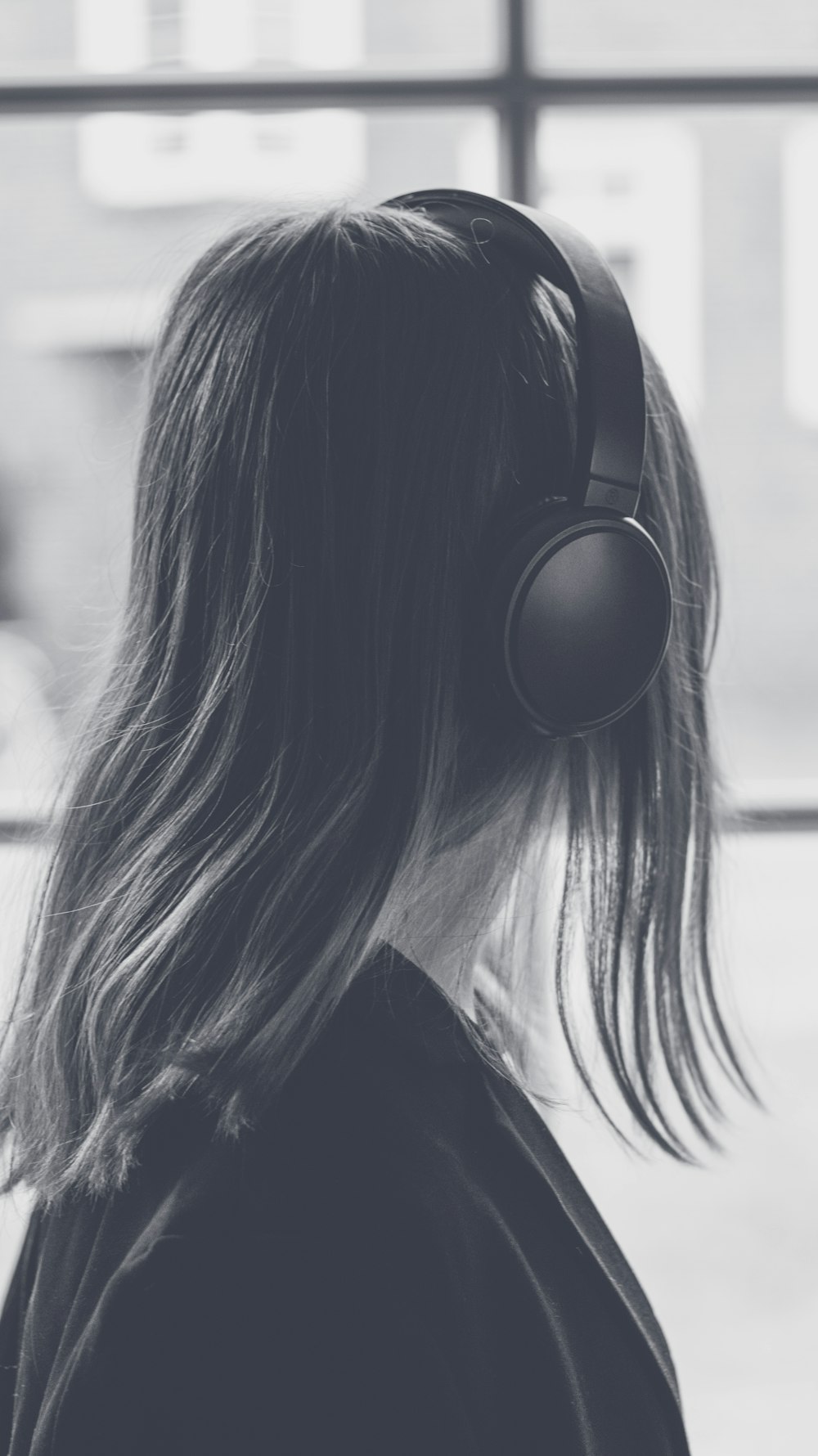 a woman wearing headphones looking out a window