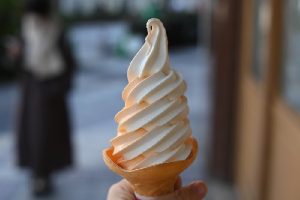 Una mano sosteniendo un cono de helado en una calle de la ciudad