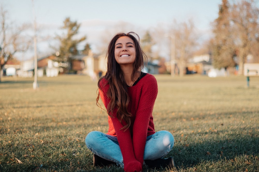 a woman sitting on the ground in a park