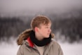 a young man standing in the snow wearing a jacket