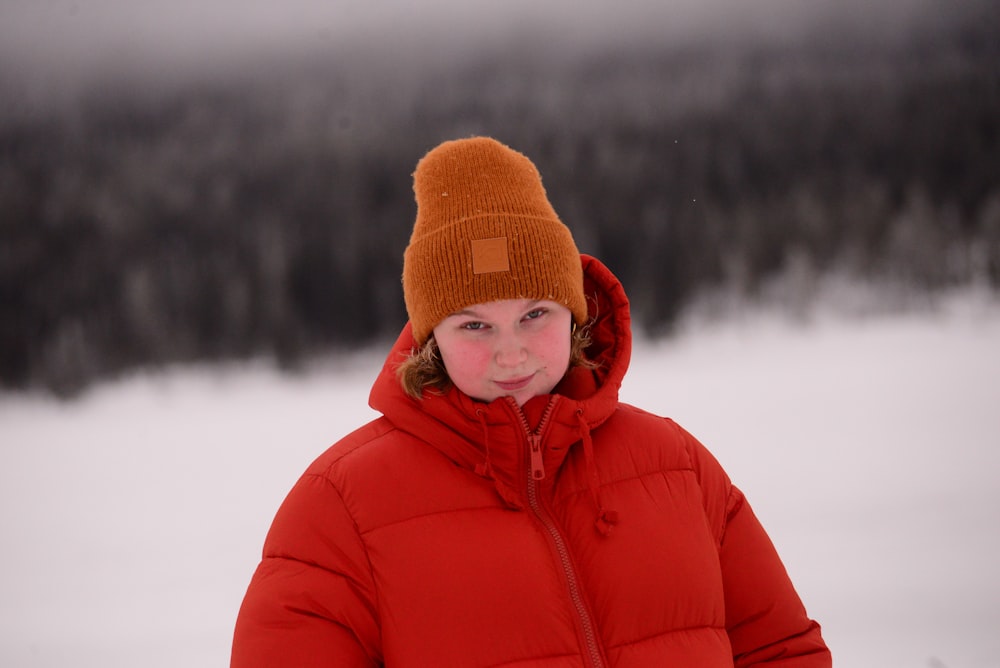 a little girl in a red jacket and a brown hat