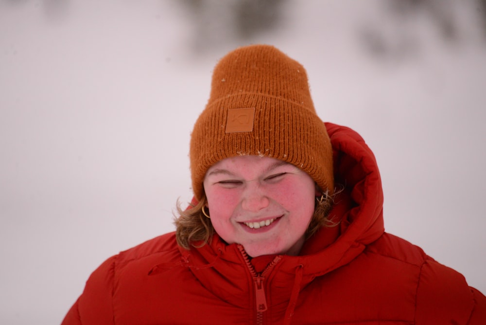 a woman in a red jacket and a brown hat