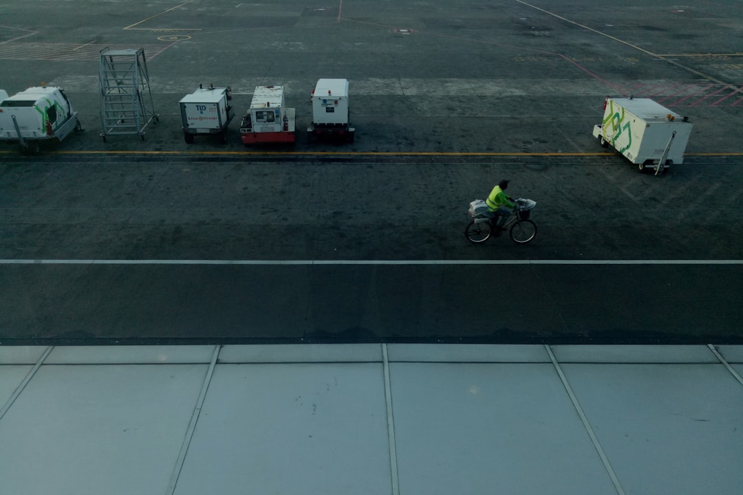 a man riding a bike past a bunch of boxes, Someone riding a bike in airport runway