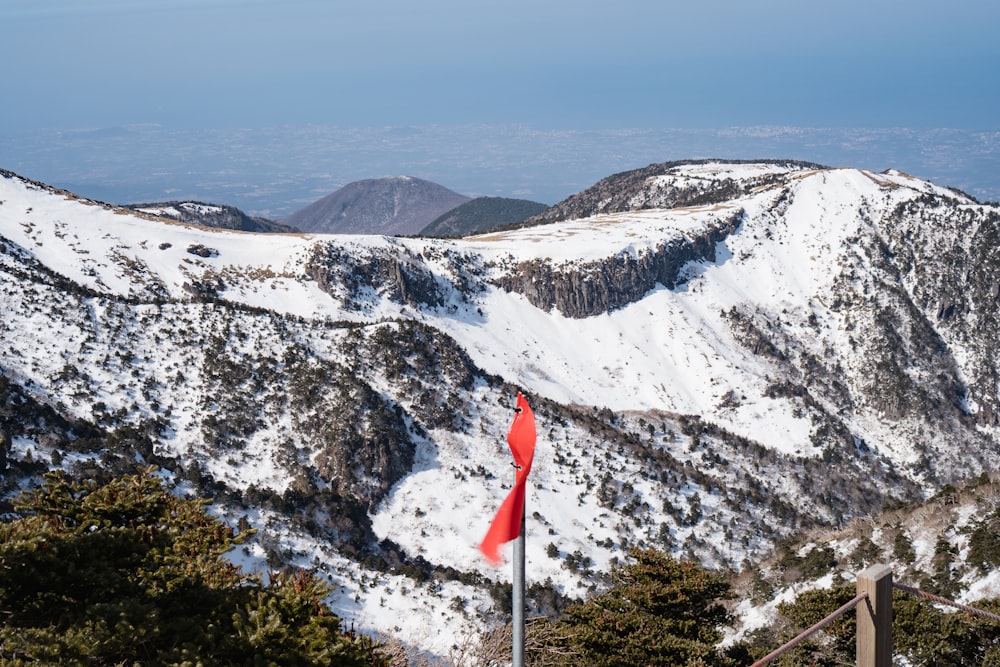 a red flag on top of a mountain covered in snow