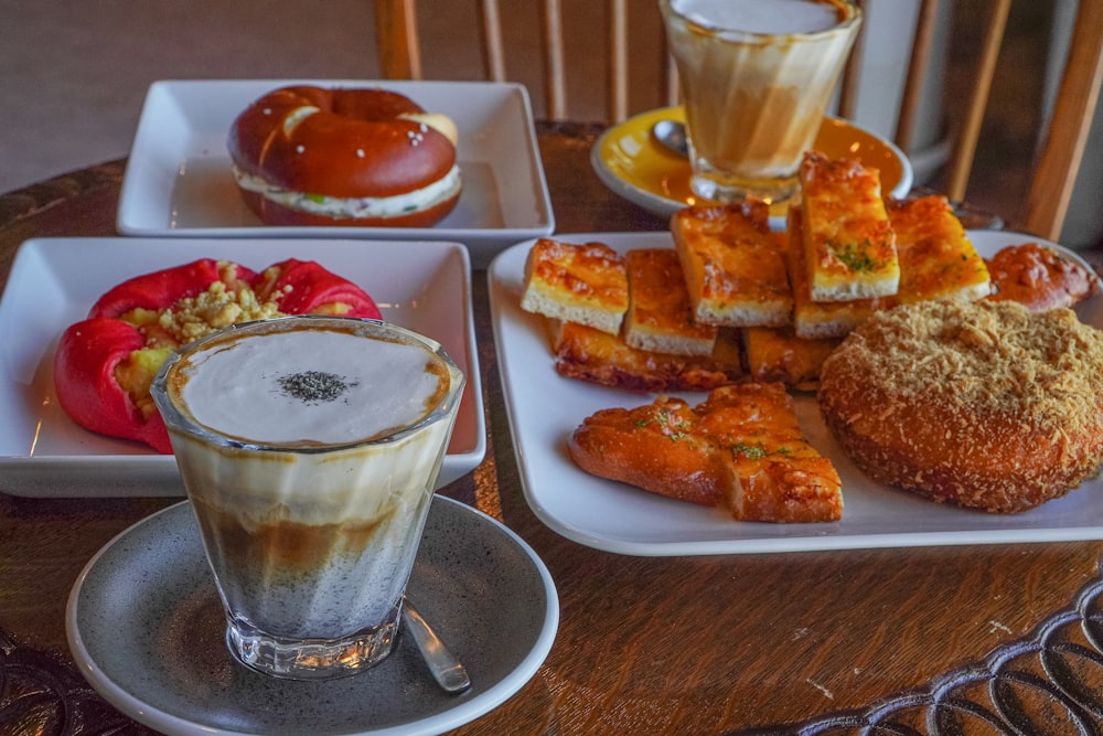 a wooden table topped with plates of food and drinks