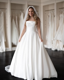 Bride smiling during a custom dress fitting in a cozy boutique.