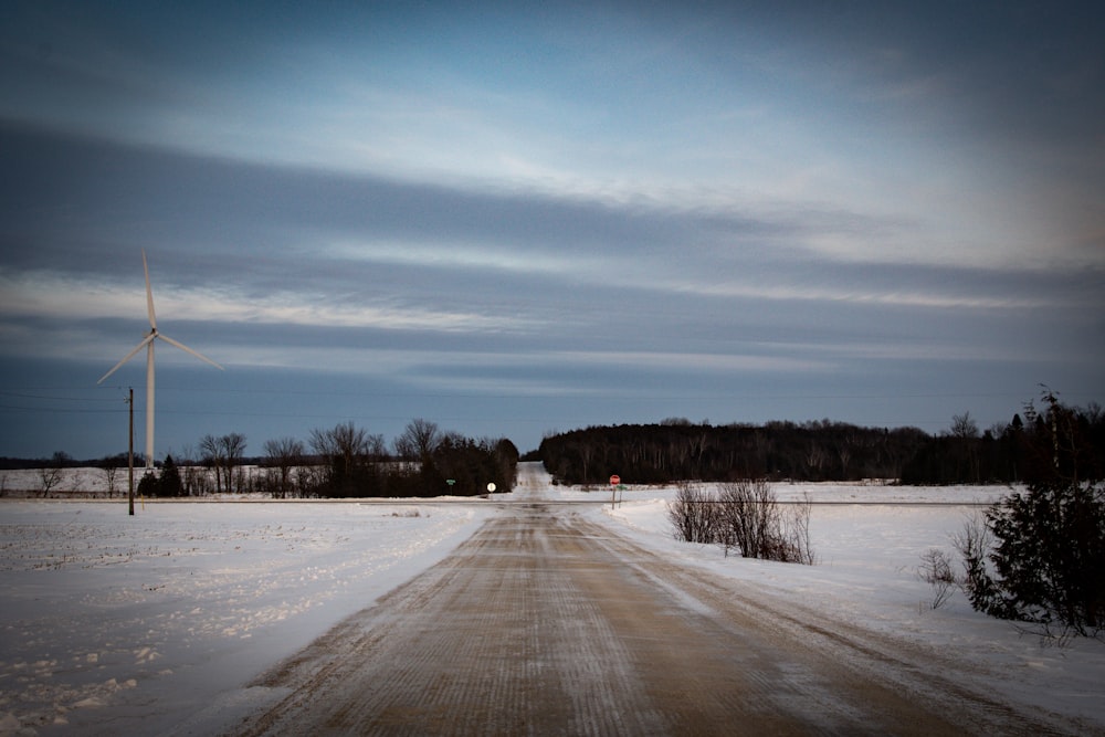 a dirt road with a wind turbine in the distance