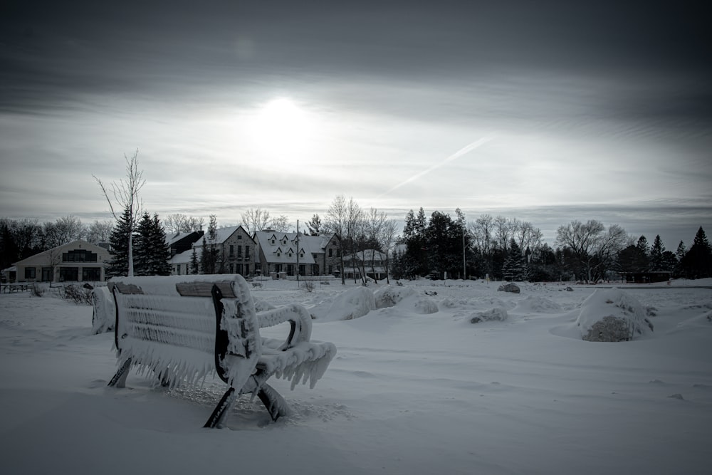 a park bench covered in snow in front of a house