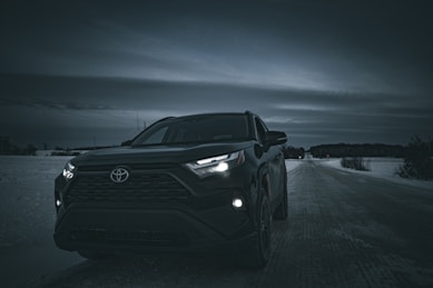 a black suv driving down a road at night