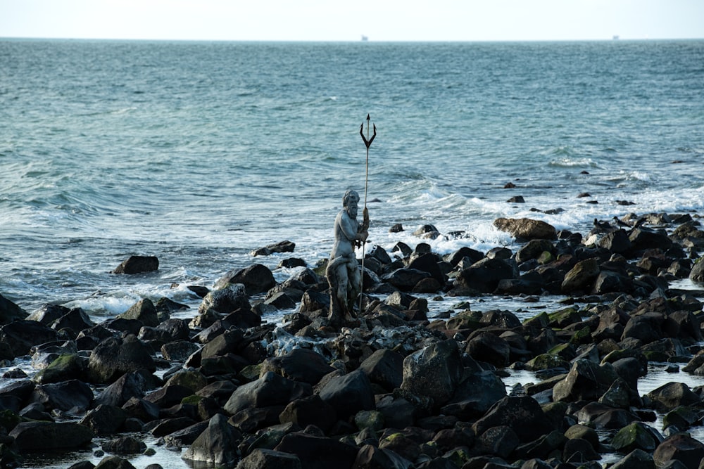 a man standing on a rocky beach next to the ocean