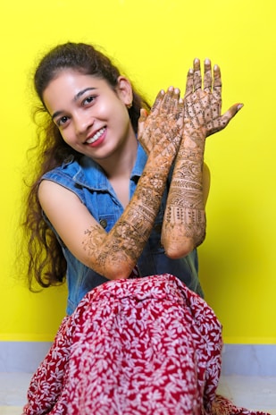 Vibrant lifestyle photo of a young girl smiling, showcasing playful henna art on her hands.