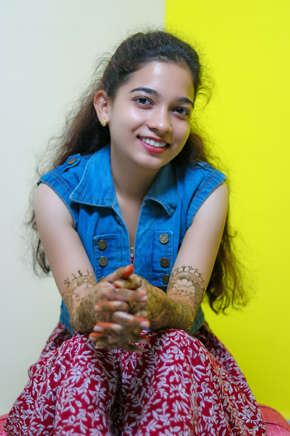 a girl sitting on a bed with her hands covered in henna