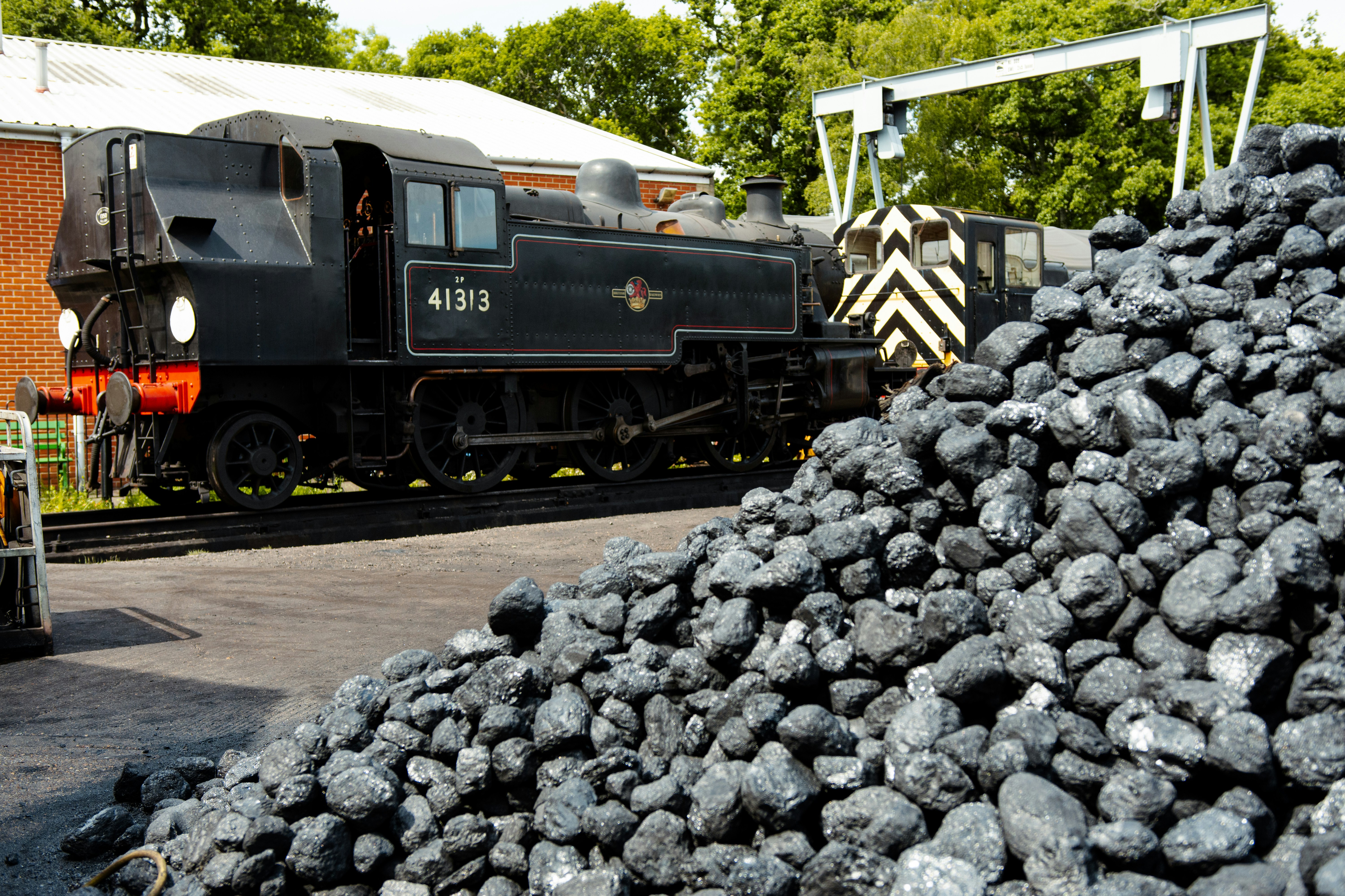 a train on a train track next to a pile of coal, 