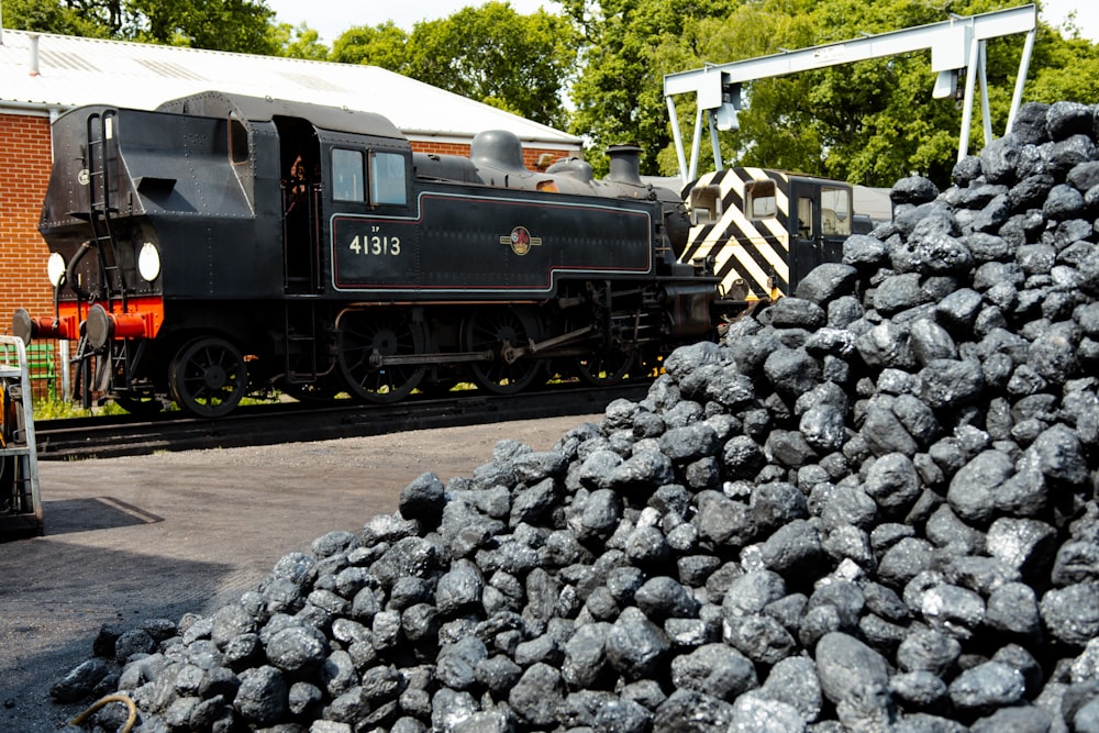 a train on a train track next to a pile of coal