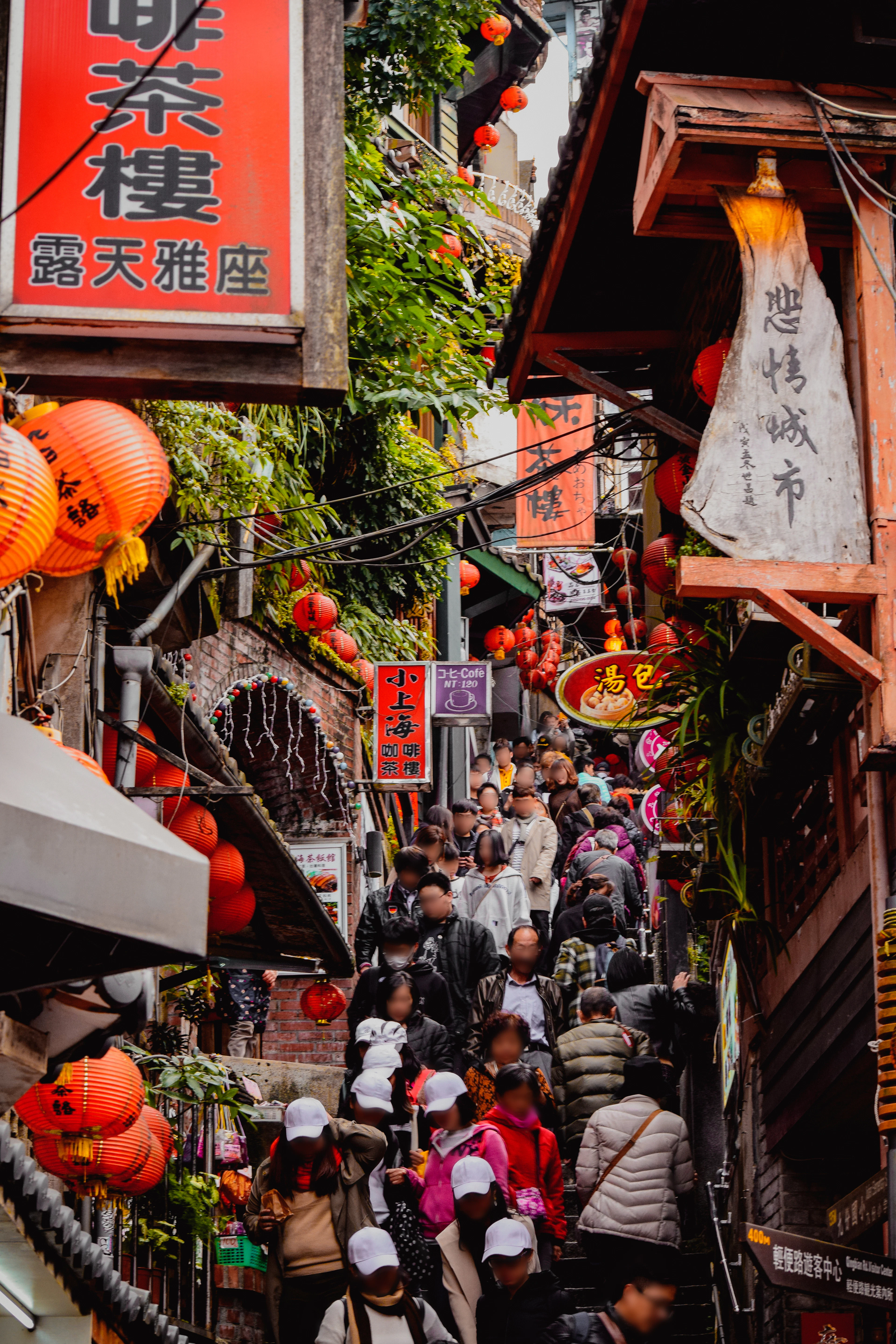 The lantern-hung lane of Jiufen Old Street packed with visitors, painted signs down both sides