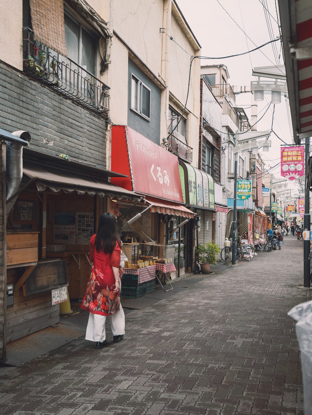 a woman in a red kimono walking down a street