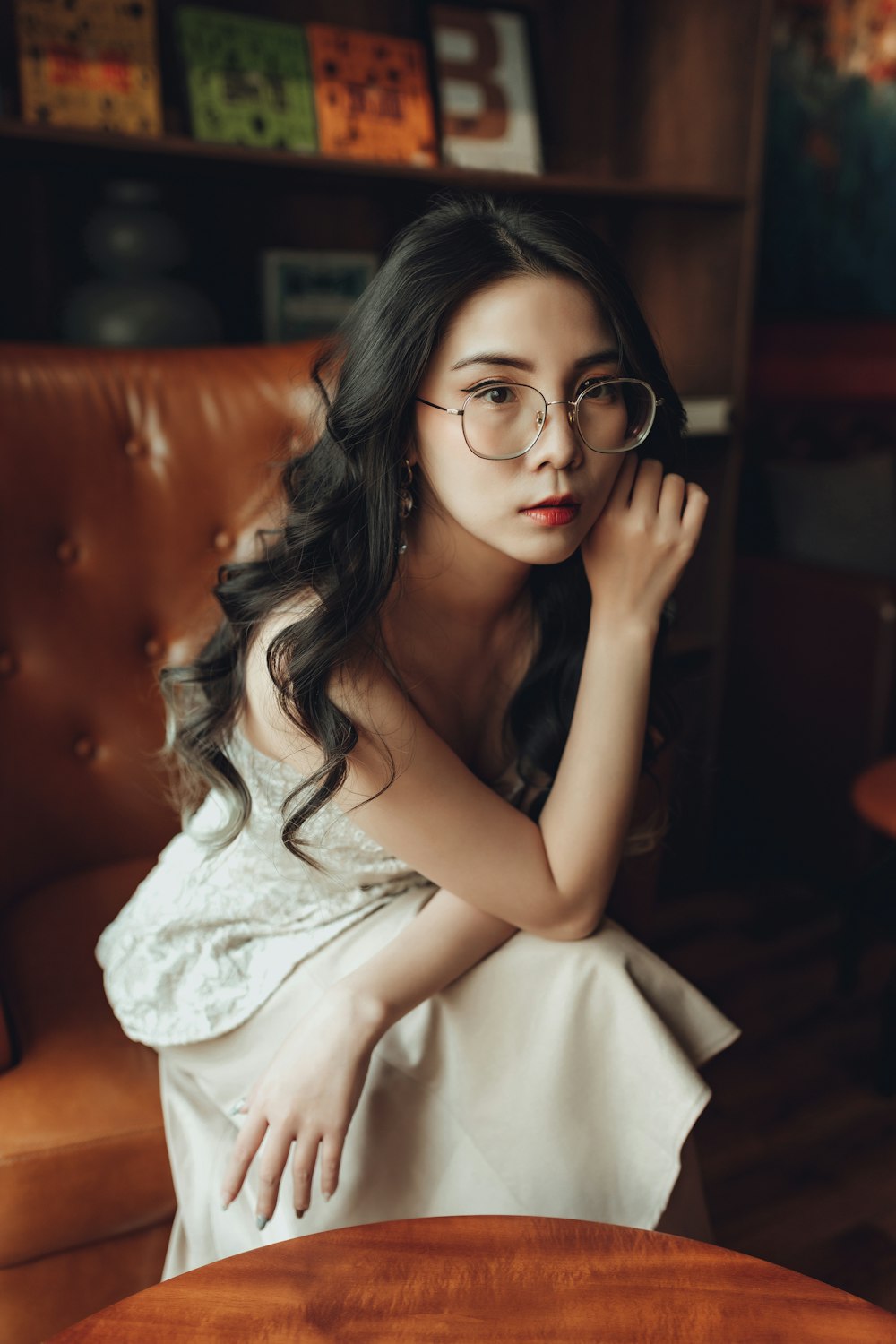 a woman wearing glasses sitting on a brown chair