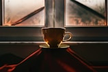 A steaming cup of tea beside a rustic wooden window.