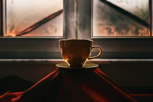 A cozy coffee cup steaming beside holiday decorations and a sunny window.