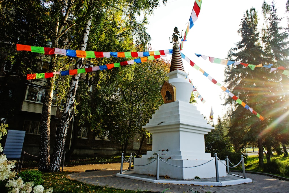 Un monument blanc avec une cloche au milieu d’un parc