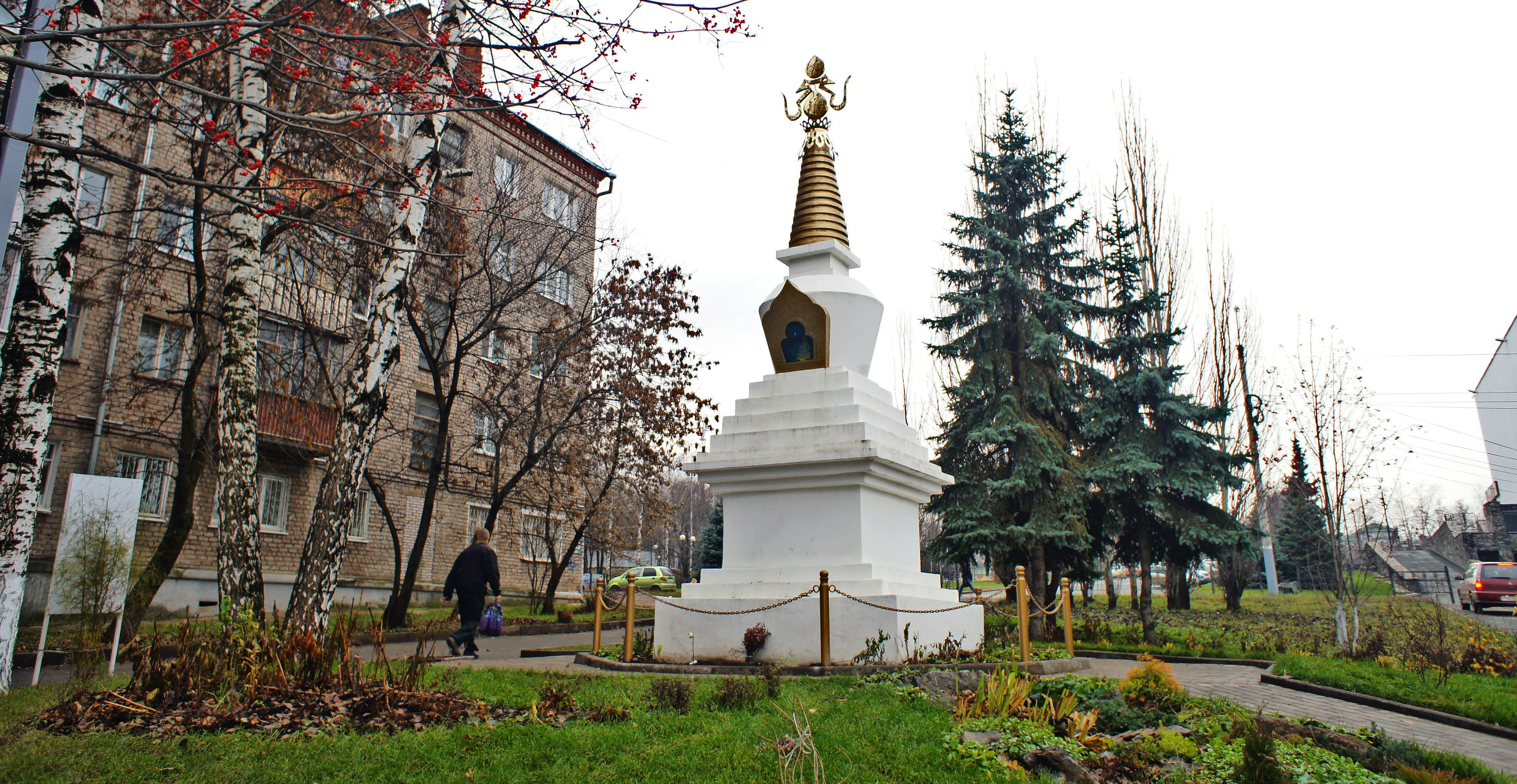 a white monument with a gold spire in the middle of a park